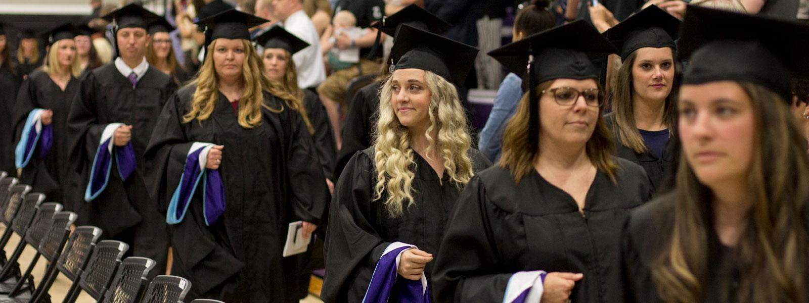 graduates walk in commencement processional holding master's hoods