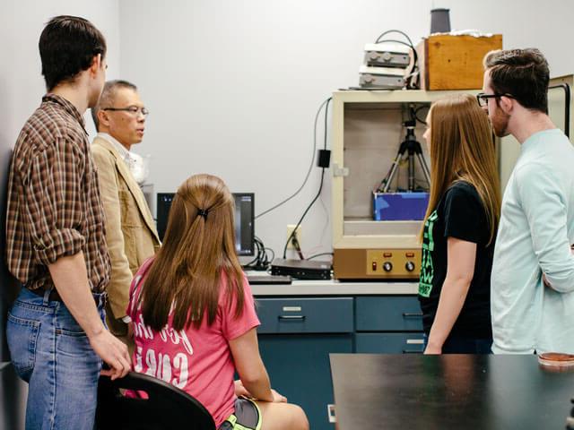 Professor explains chemistry lab equipment to group of students